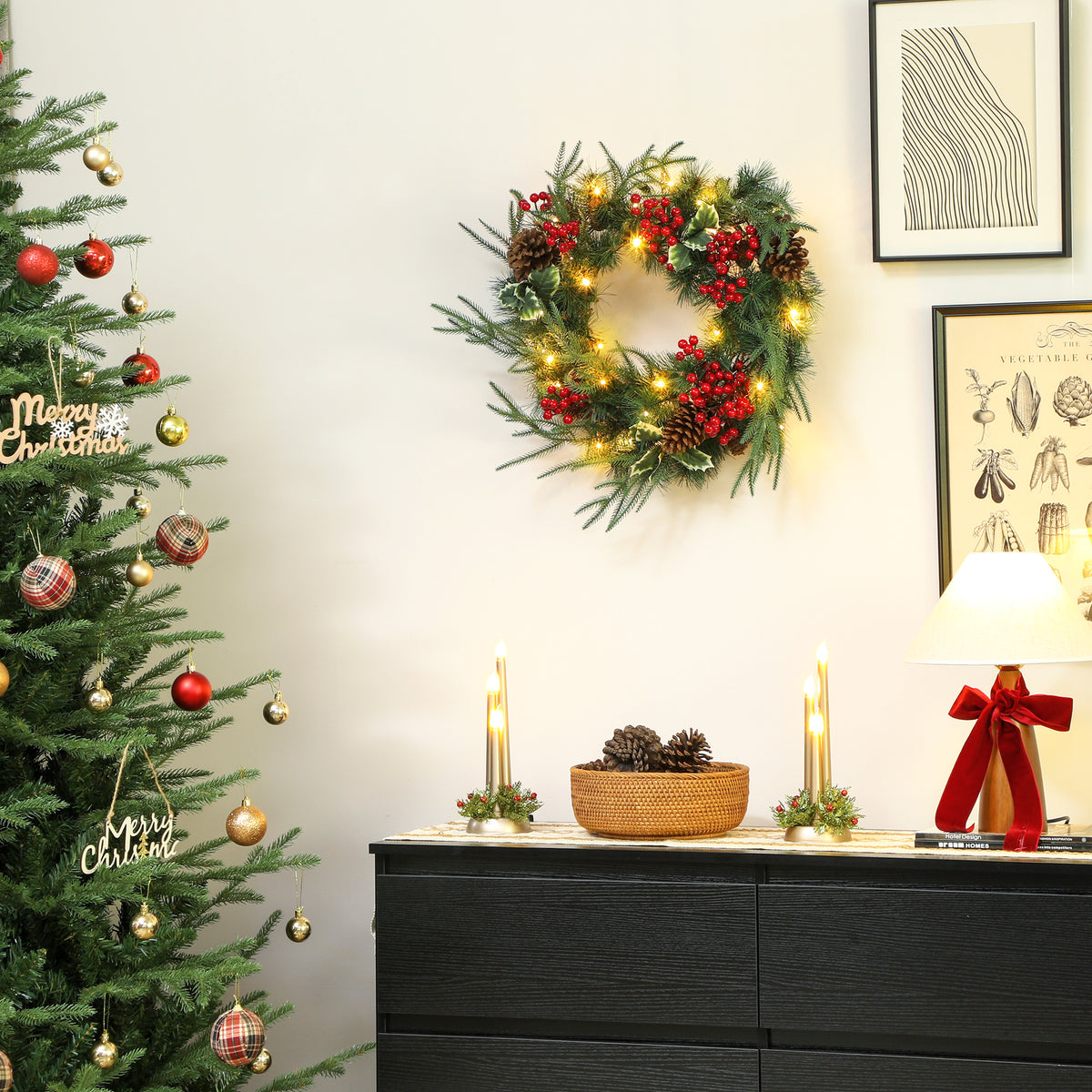 Corona de Navidad con luces cálidas colgada en una pared blanca junto a un árbol de Navidad y una cómoda negra