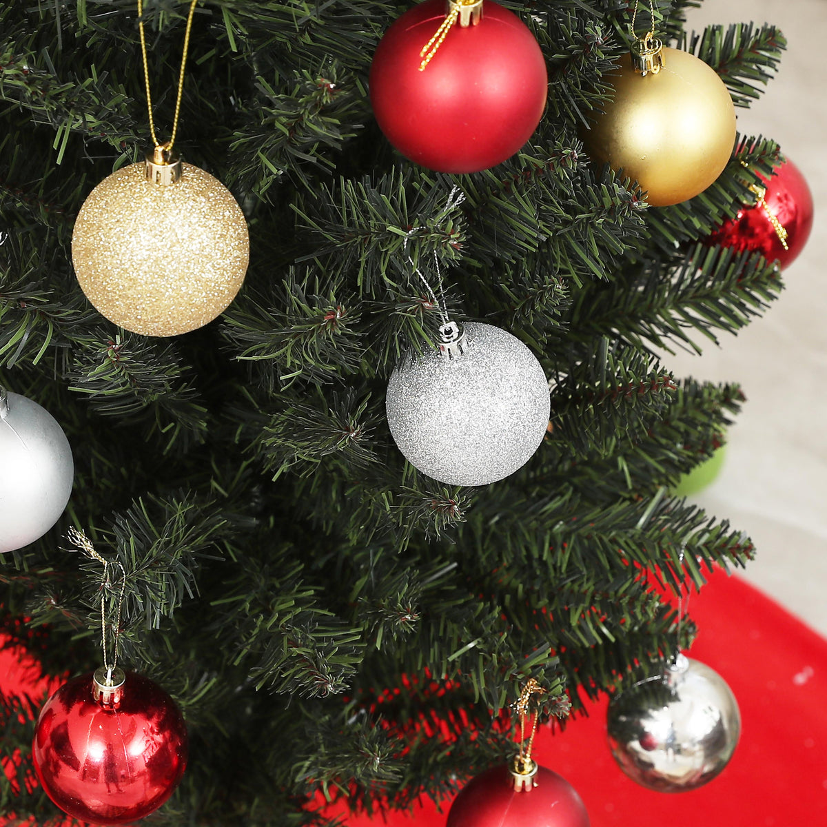 Detalle de bolas de Navidad rojas, doradas y plateadas colgadas del abeto