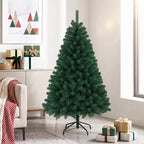 Abeto de Navidad artificial junto a una pared con cuadros de colores y cajas de regalo