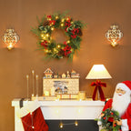 Corona de Navidad con luces cálidas colgada en una pared sobre una repisa con un calendario de Adviento y Papá Noel