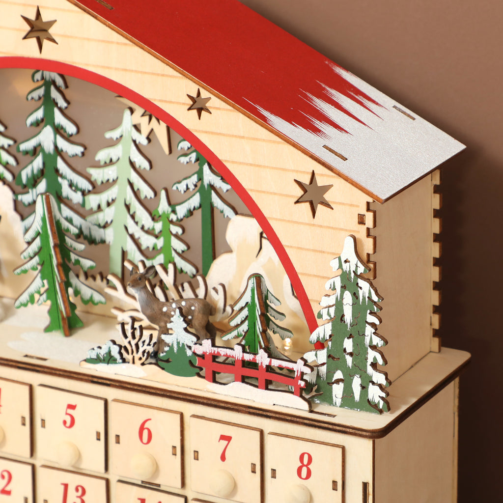 Detalle de la escena de bosque con renos, árboles y tren sobre los cajones del calendario de Adviento