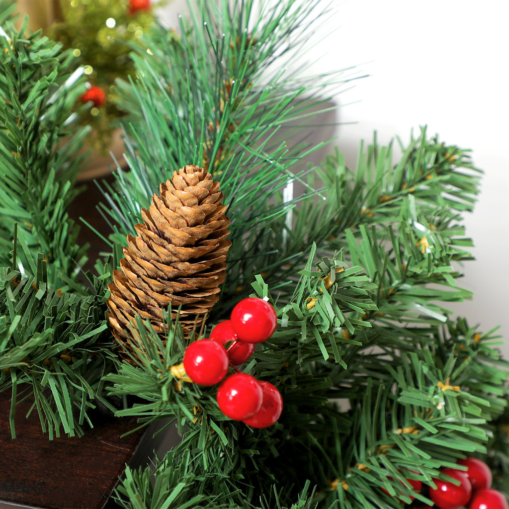 Detalle de una piña y bayas rojas entre las ramas verdes de la guirnalda de Navidad