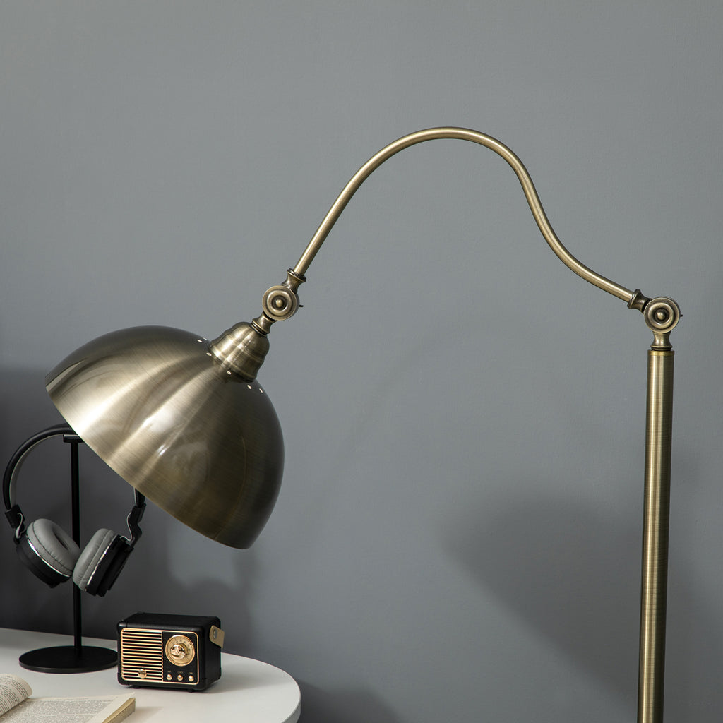 Pantalla orientable y brazo curvo de la lámpara de pie bronce junto a unos auriculares