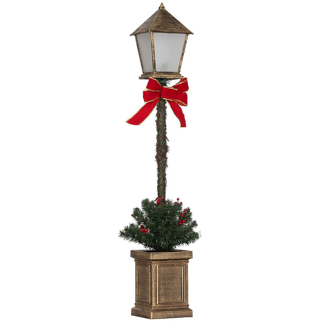 Farol de Navidad LED con linterna de bronce, lazo rojo y pequeño árbol verde en una maceta, vista frontal sobre fondo blanco