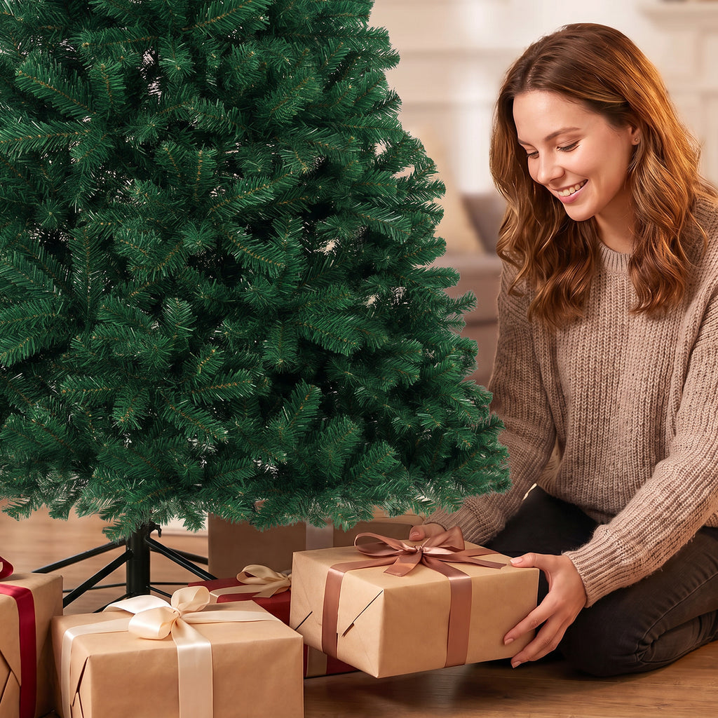 Mujer sonriente abriendo un regalo junto al abeto de Navidad