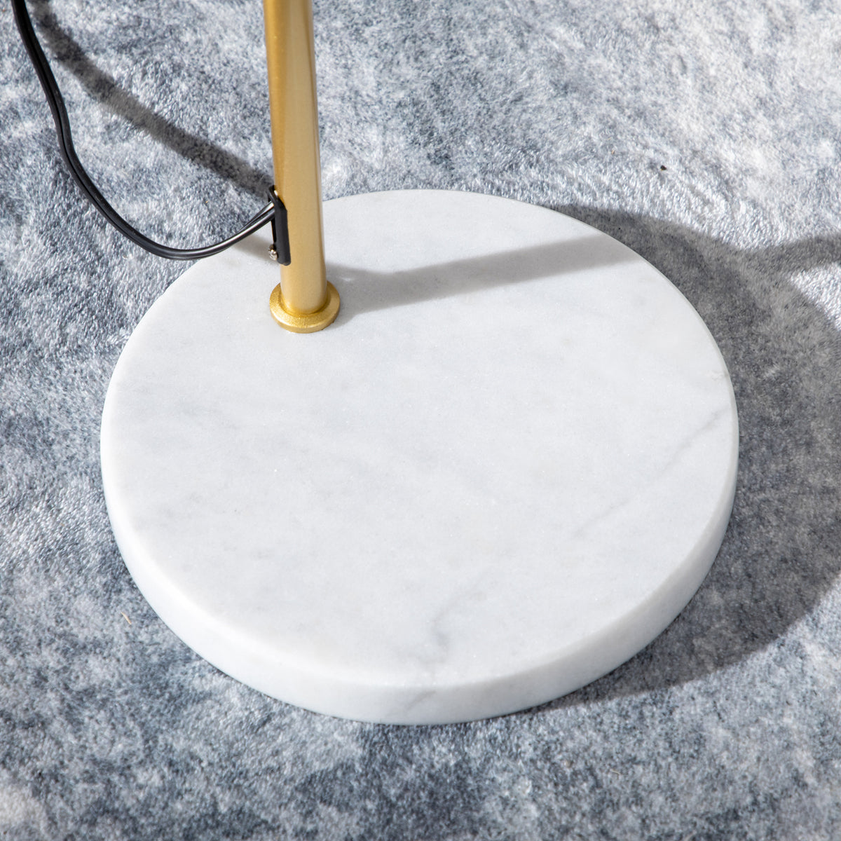 Detalle de la base redonda de mármol blanco y el cable de la lámpara de pie