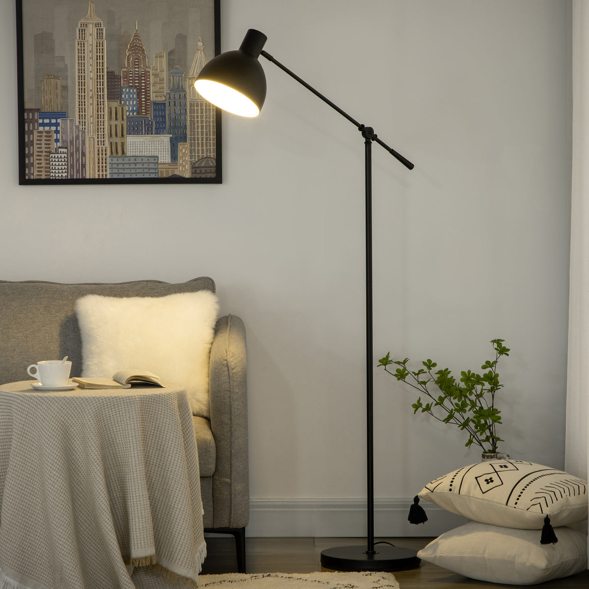 Lámpara de pie negra encendida junto a un sillón gris con cojines y una planta
