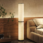 Lámpara de pie LED en columna encendida junto a un sofá y una planta en un salón