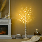 Árbol de abedul con luces LED junto a una chimenea y adornos navideños