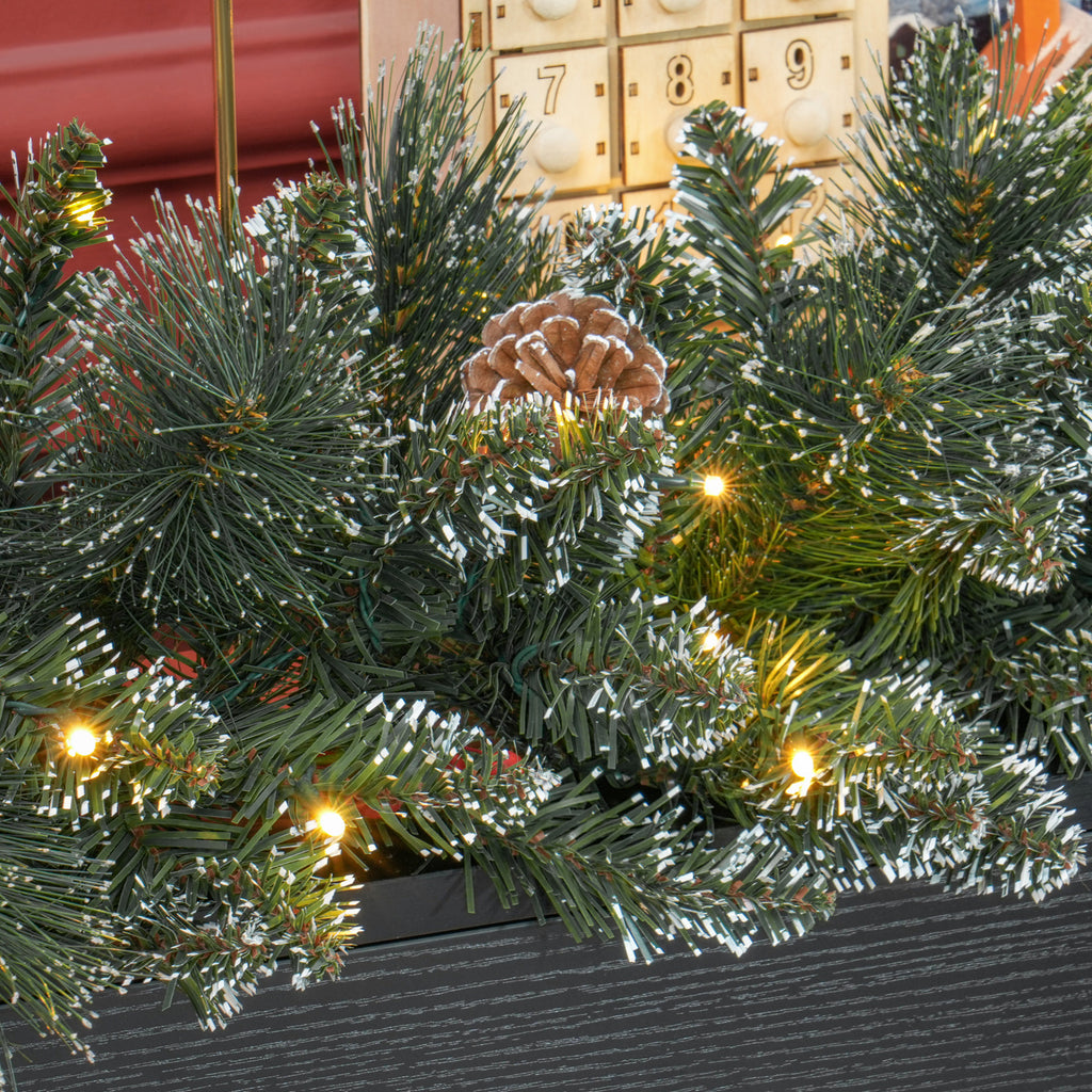 Detalle de las ramas de la guirnalda con piñas y luces LED sobre una consola