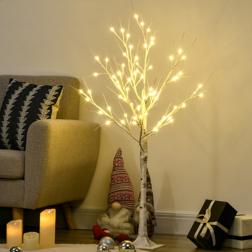Árbol de abedul con luces LED junto a un sofá, velas y adornos navideños