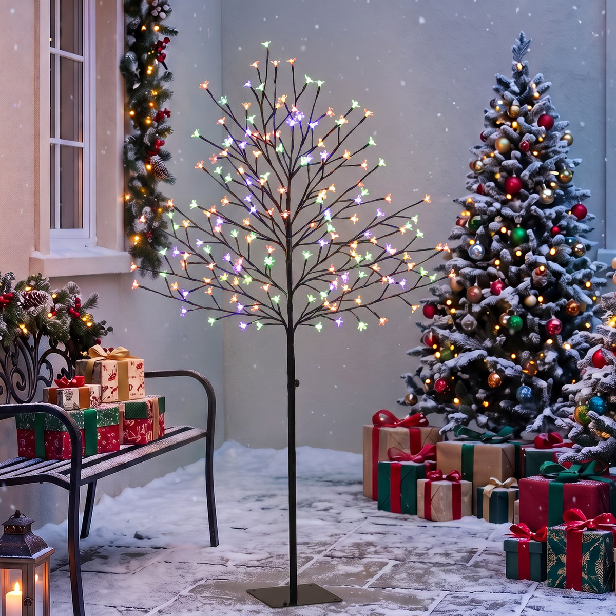 Árbol de cerezo luminoso multicolor en una terraza cubierta junto a un árbol de Navidad y regalos