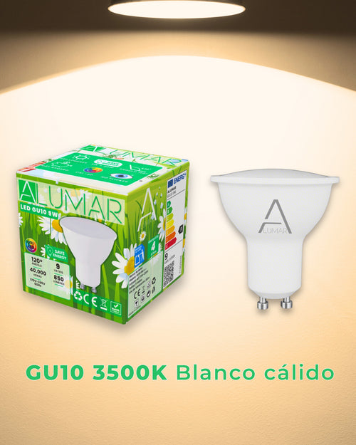 Bombilla LED GU10 9W 3500K Blanco cálido ALUMAR con su caja junto a una pared iluminada con luz cálida