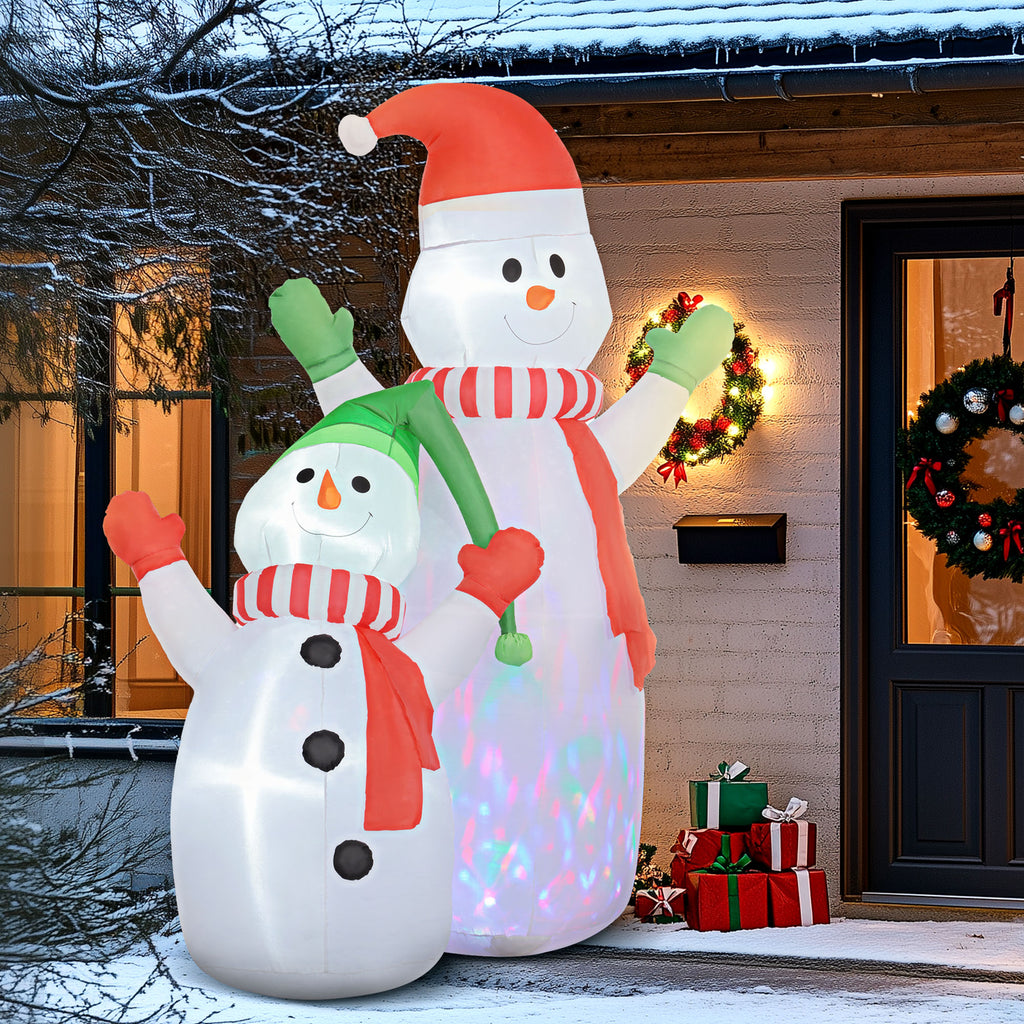 Dúo de muñecos de nieve hinchables junto a la puerta de una casa decorada con coronas navideñas