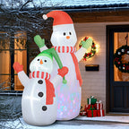 Dúo de muñecos de nieve hinchables junto a la puerta de una casa decorada con coronas navideñas