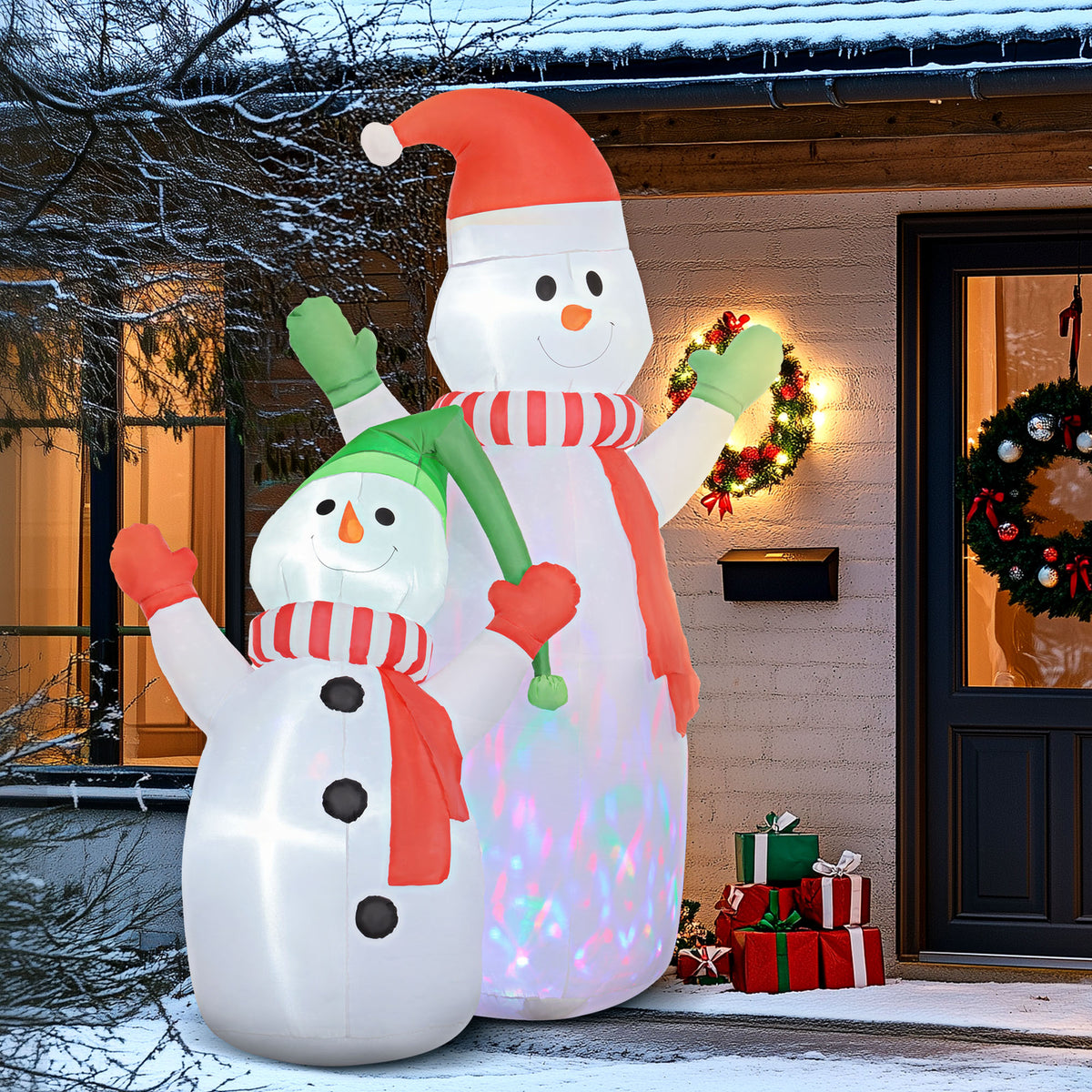 Dúo de muñecos de nieve hinchables junto a la puerta de una casa decorada con coronas navideñas
