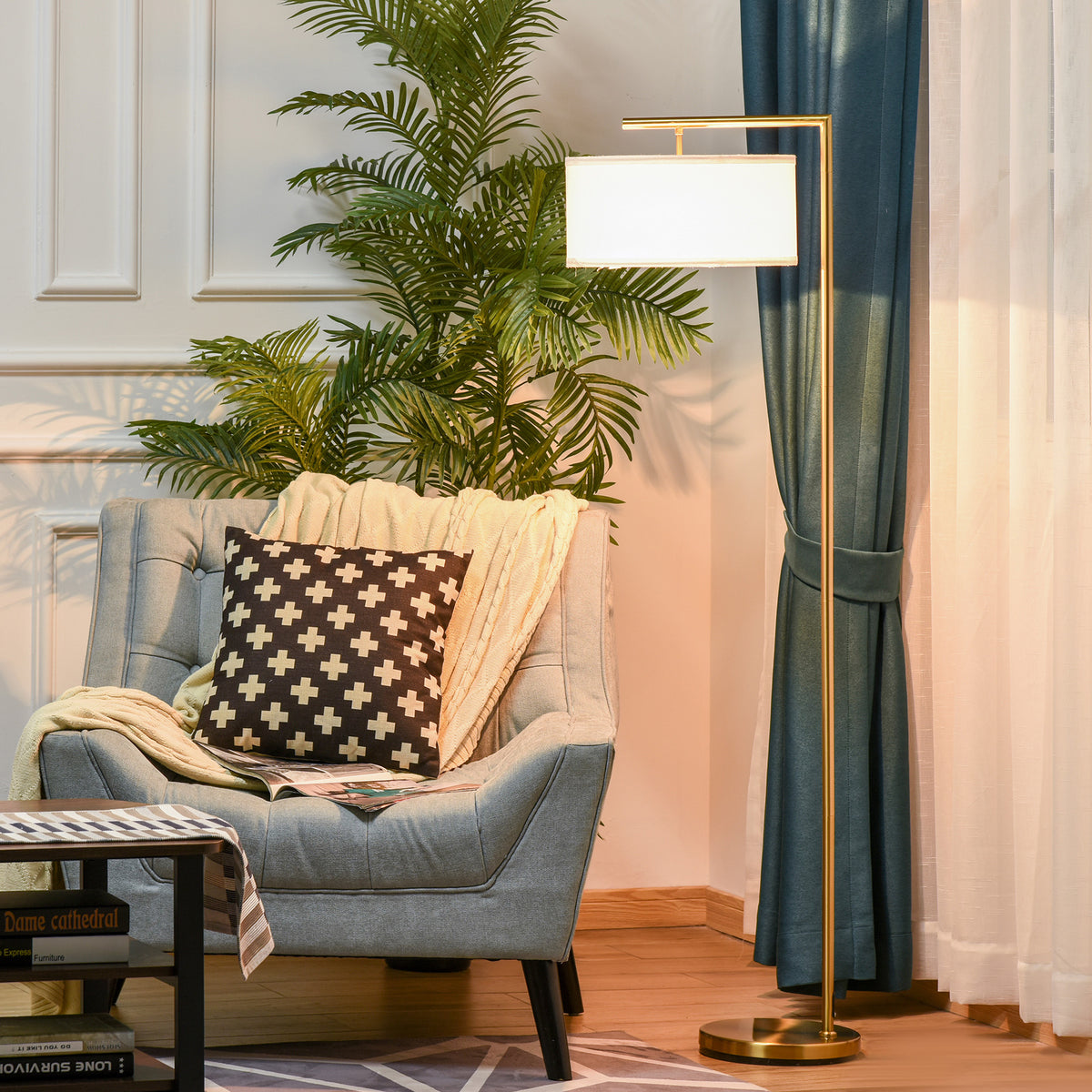 Lámpara de pie dorada con pantalla de lino junto a un sillón azul y una cortina