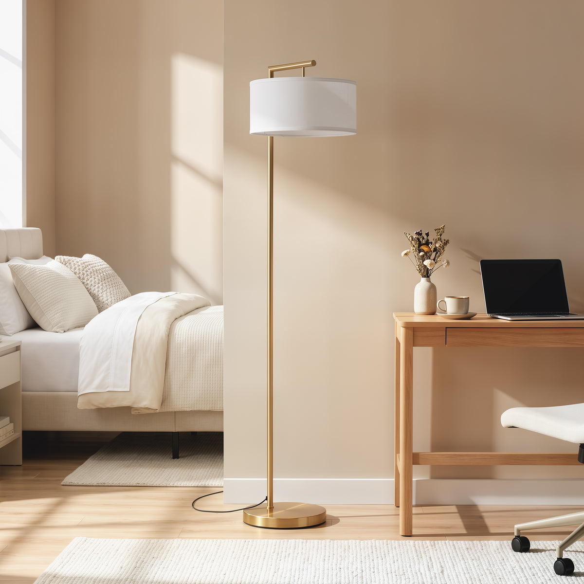 Lámpara de pie dorada con pantalla de lino junto a una cama y un escritorio en un dormitorio