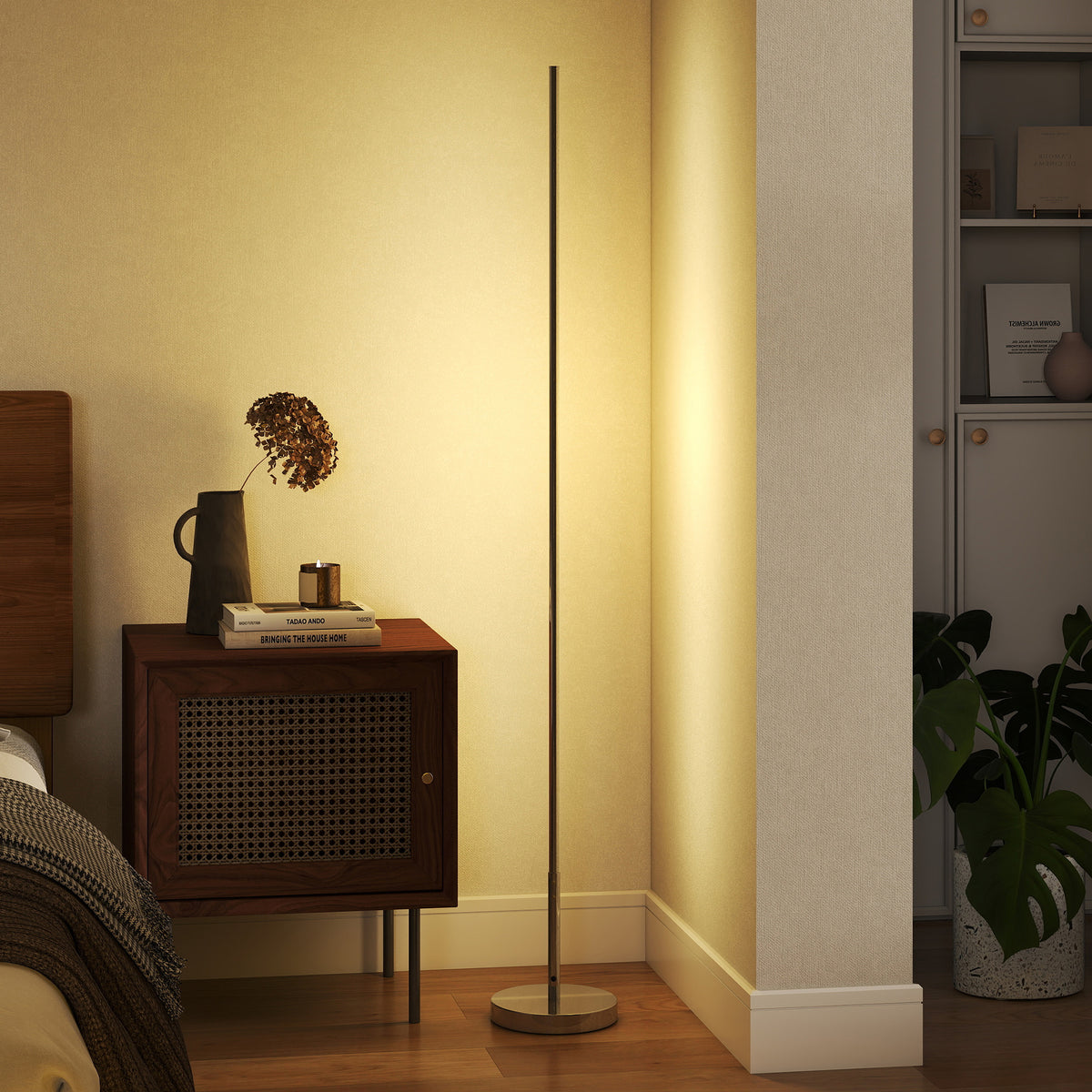 Lámpara de pie LED encendida junto a una mesita de noche de ratán en un dormitorio
