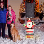 Medidas del Papá Noel luminoso: 93 cm de alto, 52 cm de ancho y 30 cm de fondo, junto a dos personas y un perro