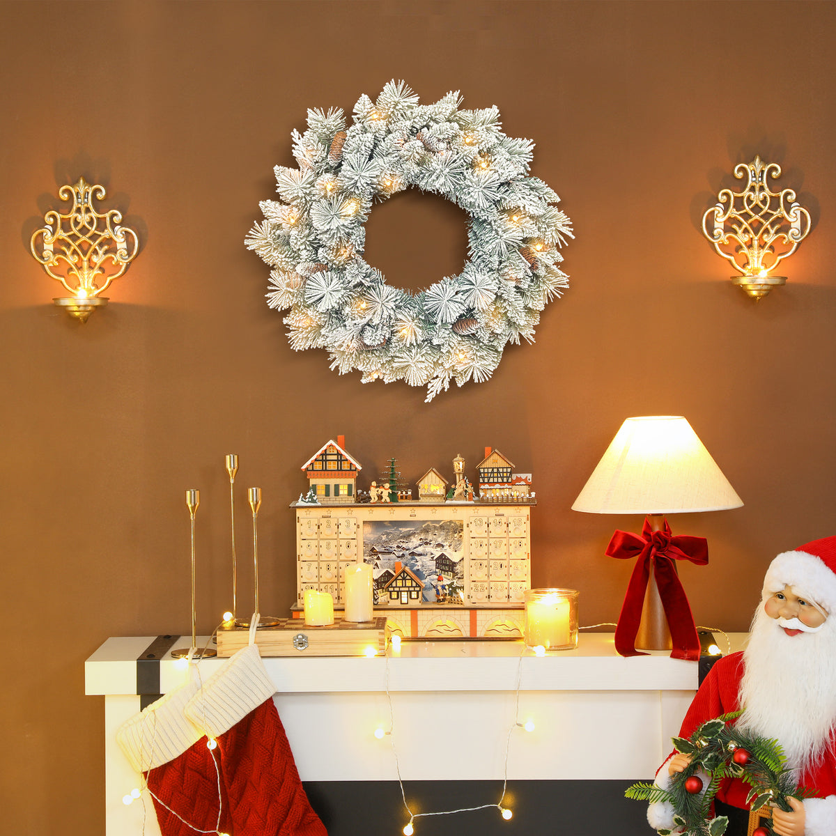 Corona de Navidad nevada colgada en una pared sobre una repisa con velas y un calendario de Adviento