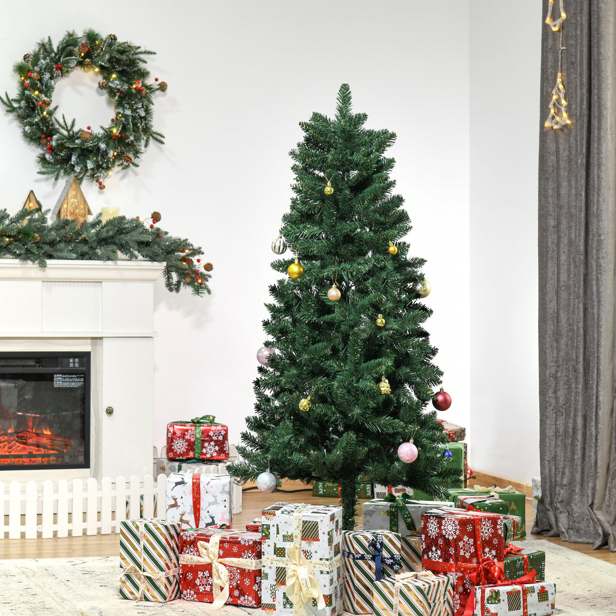 Abeto de Navidad artificial junto a una chimenea con una corona y regalos