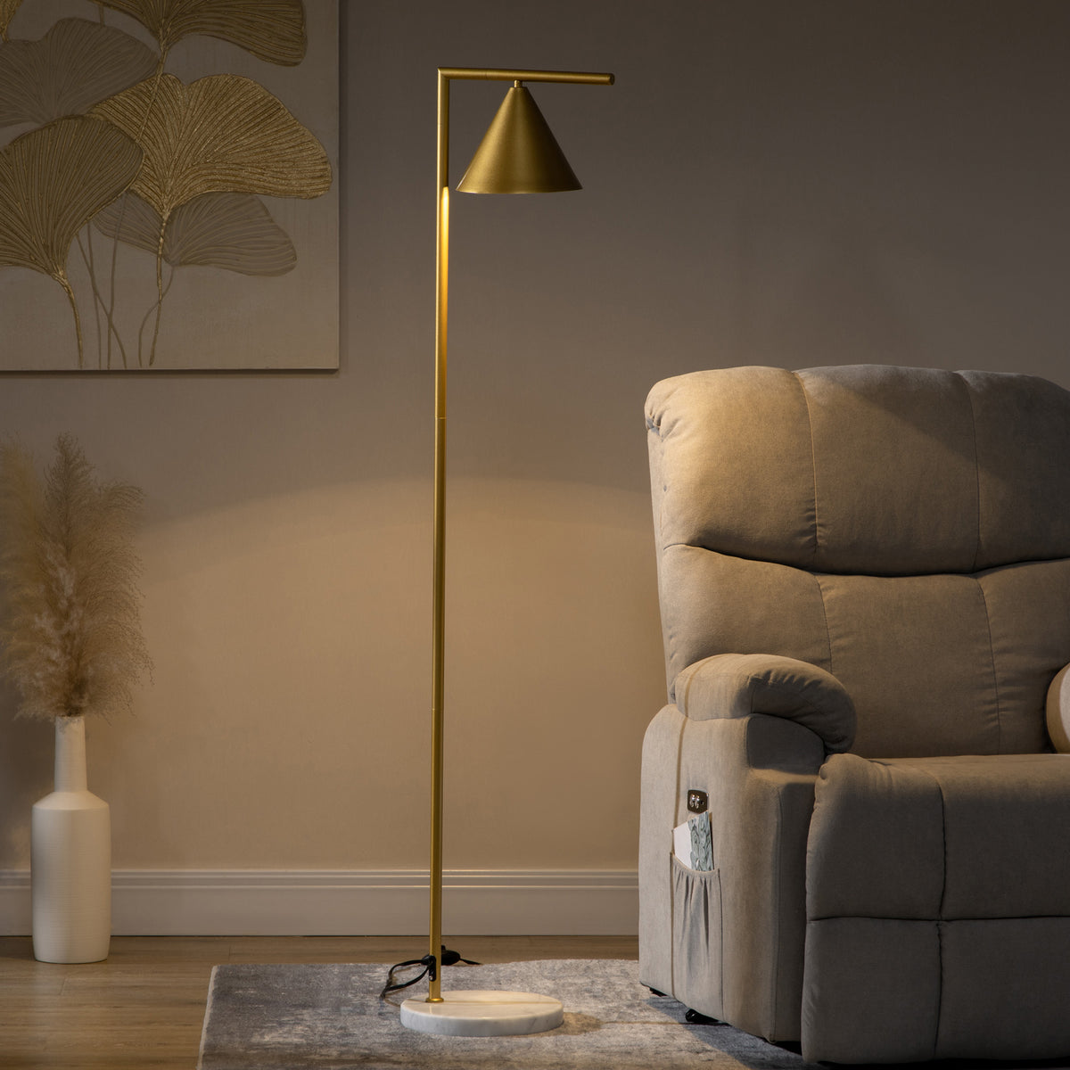 Lámpara de pie dorada encendida junto a un sillón y un jarrón en un salón