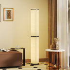 Lámpara de pie LED en columna encendida junto a un banco y una mesita en un salon