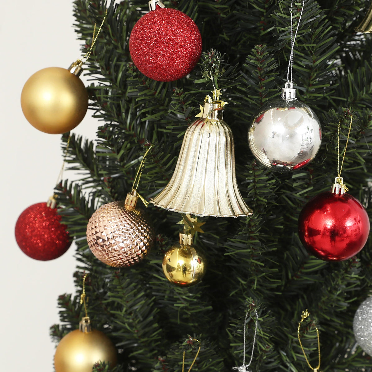 Abeto de Navidad estrecho decorado con bolas rojas, doradas y plateadas, detalle de las ramas