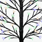 Detalle de las ramas del árbol luminoso con flores en luz multicolor
