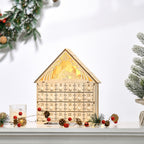 Calendario de Adviento de madera iluminado en una repisa junto a velas y un árbol
