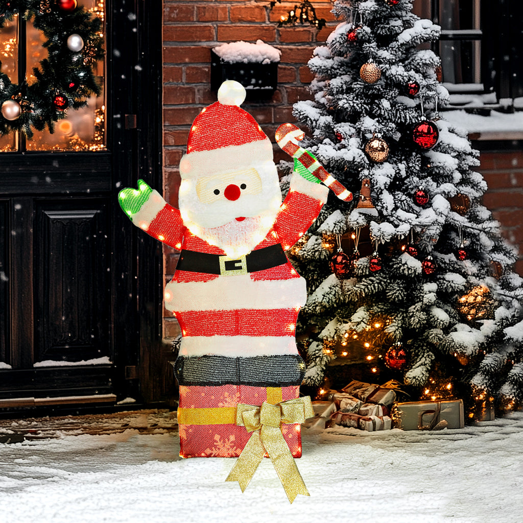 Papá Noel luminoso junto a un árbol de Navidad nevado y una puerta decorada