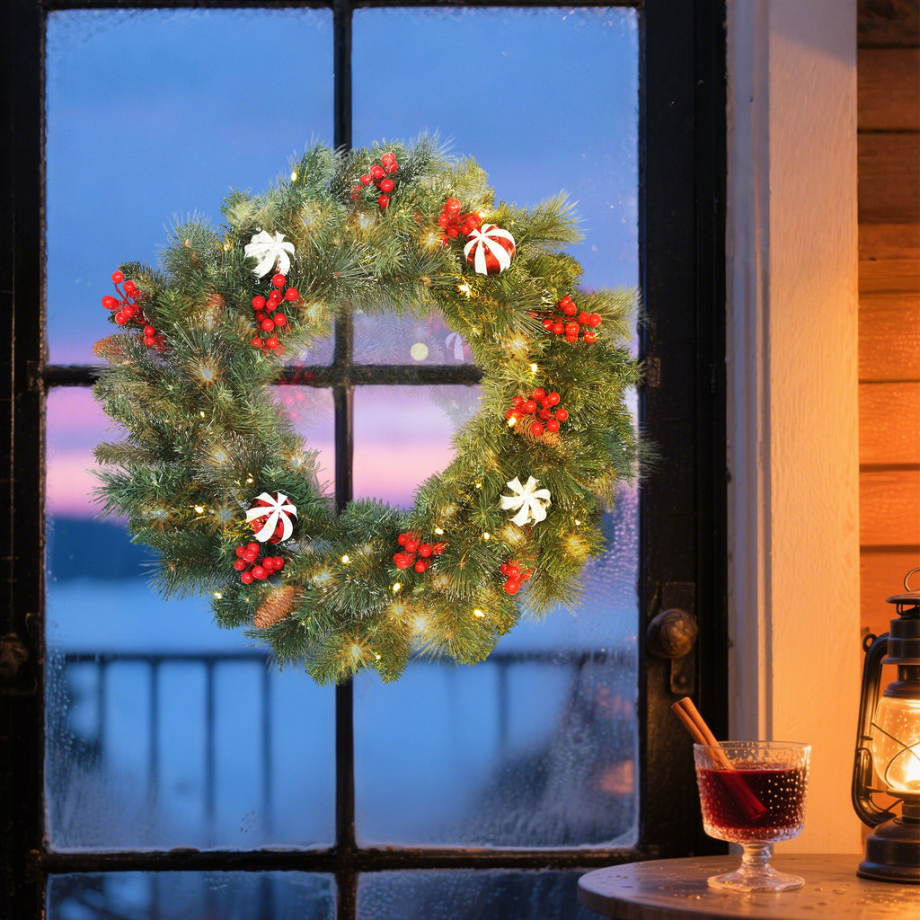 Corona de Navidad iluminada colgada en una ventana al atardecer junto a una copa de vino caliente