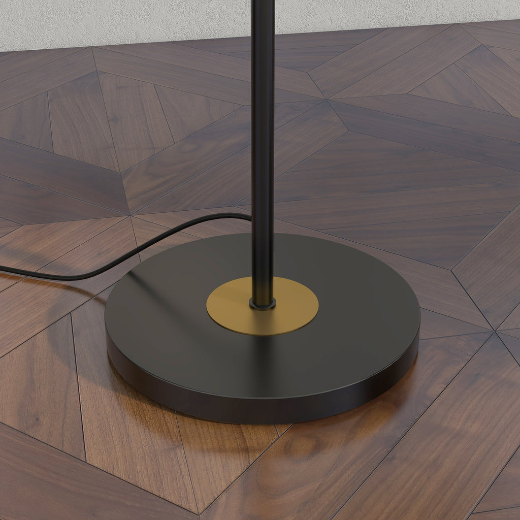 Detalle de la base redonda negra con centro dorado y el cable de la lámpara de pie