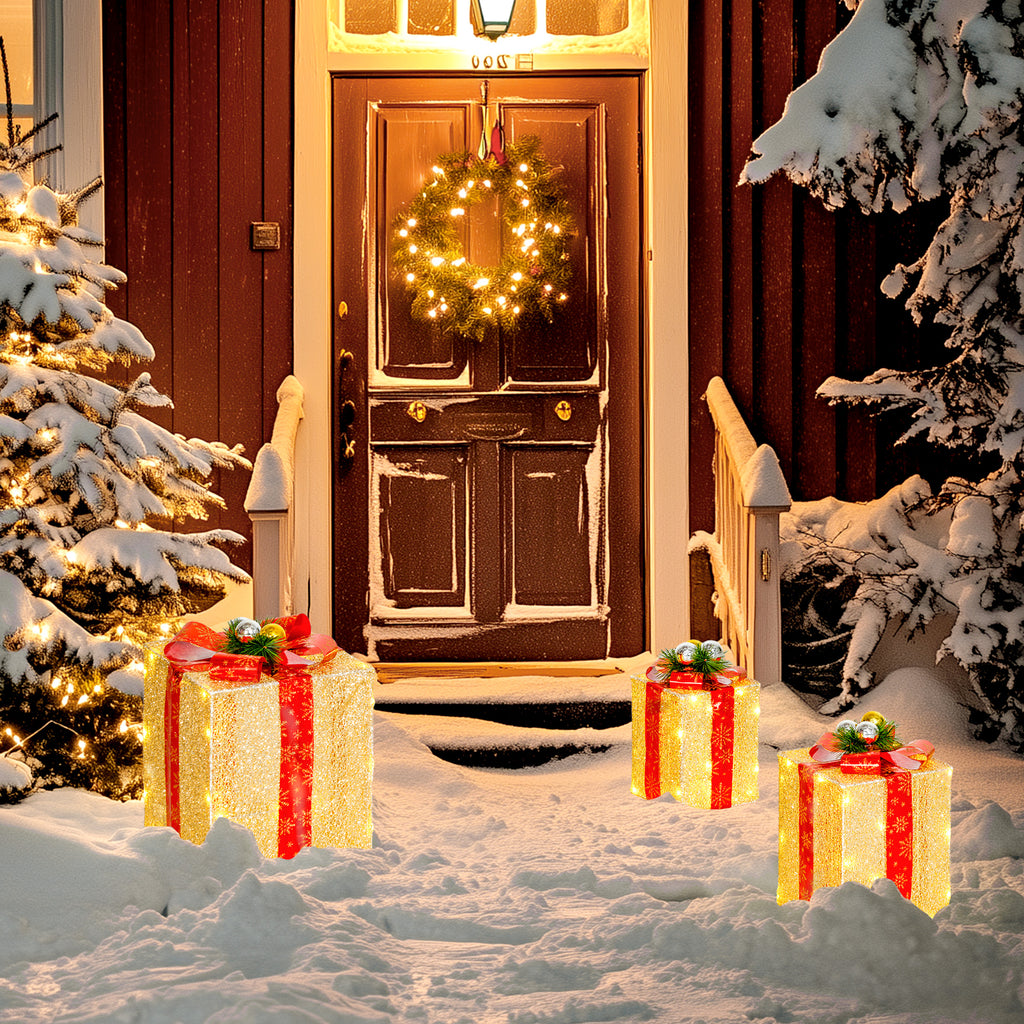 Cajas de regalo luminosas junto a una puerta de madera con corona y nieve por la noche